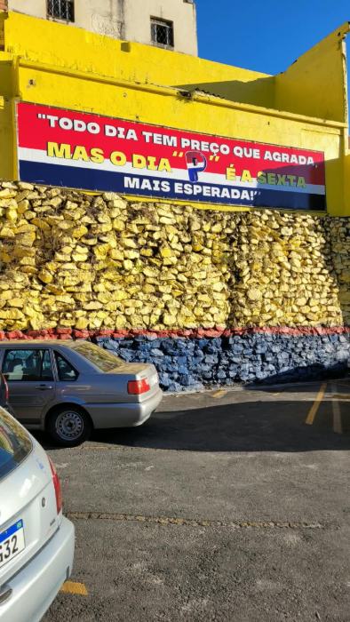 Faixa em lona instalada em muro de supermercado